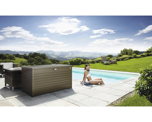 Scéna s kovovým úložným boxem vedle bazénu, obklopeného zahradním nábytkem a ženou sedící ve vodě.