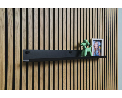 Černá nástěnná police před dřevěnou obkladovou stěnou s dekorací