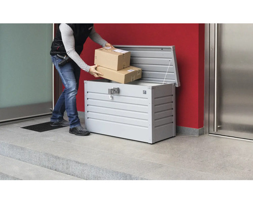 Doručovatel vkládá balíky do kovové schránky na balíky