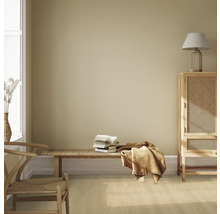 Světlá místnost s dřevěným nábytkem, lavicí, hromadou knih a textilem pro útulnou atmosféru.