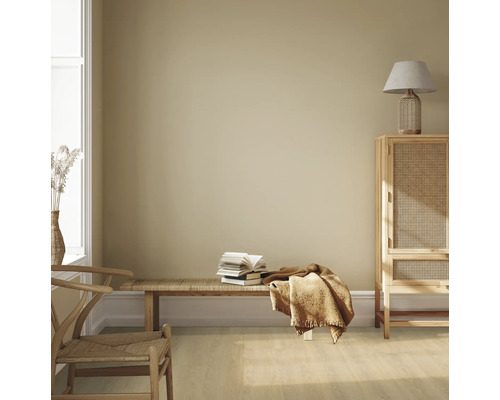 Světlá místnost s dřevěným nábytkem, lavicí, hromadou knih a textilem pro útulnou atmosféru.