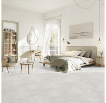 Světlá ložnice s postelí, posezením, skříní a dekoracemi na světlé podlaze