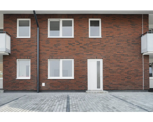 Fasáda domu s cihlovou zdí, bílými okny a dveřmi