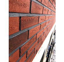 Detail fasády s červenými cihlami a šedými spárami