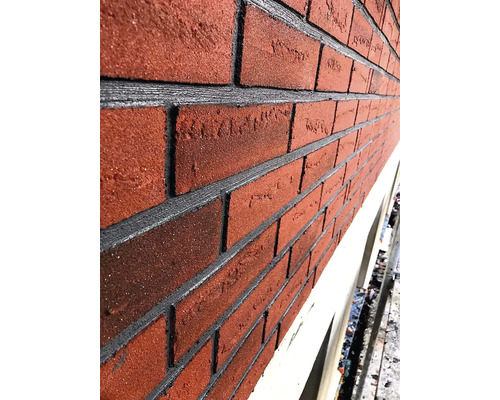 Detail fasády s červenými cihlami a šedými spárami