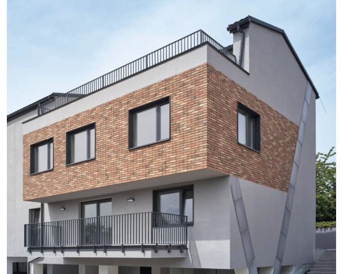 Moderní budova s cihlovou fasádou, okny a balkonem