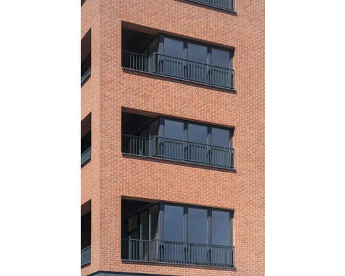 Fasáda obytné budovy s balkony a cihlovou zdí