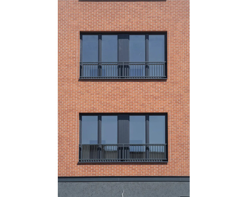 Fasáda domu s cihlovým zdivem a okny se zábradlím