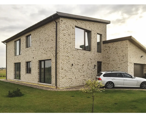 Exteriér dvoupodlažního domu s garáží, cihlovou fasádou a trávníkem