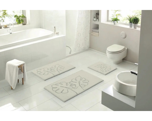 Světlá koupelna s vanou, toaletou, umyvadlem a sadou koupelnových předložek s rostlinným motivem