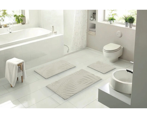 Světlá koupelna s vanou, toaletou, umyvadlem a sadou koupelnových předložek s palmovým vzorem