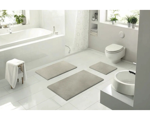 Světlá koupelna s vanou, toaletou, umyvadlem a sadou koupelnových předložek