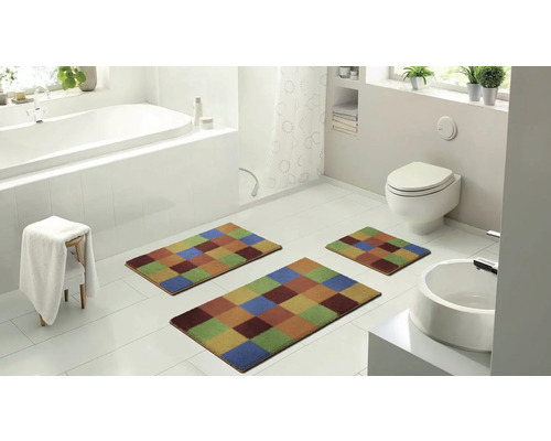 Moderní koupelna s vanou, toaletou, umyvadlem a sadou tří barevných koupelnových předložek