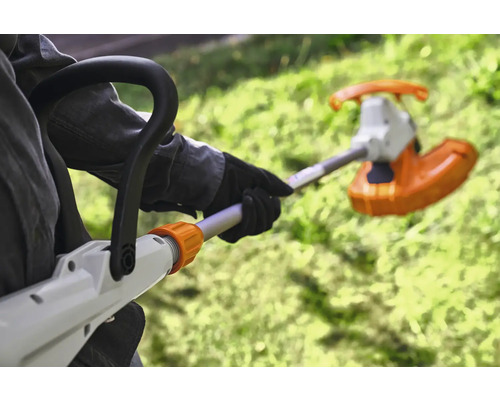 Osoba obsluhuje vyžínač na zahradě.