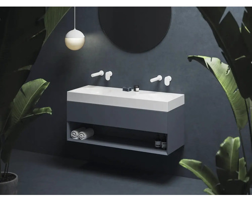 Dvojité umyvadlo s úložným prostorem, armaturami, kulatým zrcadlem a dekorací v koupelně.