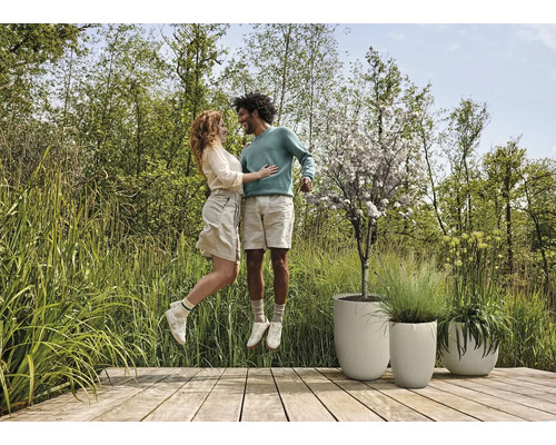 Scéna s párem na dřevěné terase vedle strukturovaných květináčů a zahrady