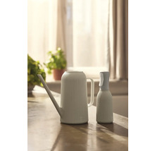 Konvička a rozprašovač na rostliny na stole.