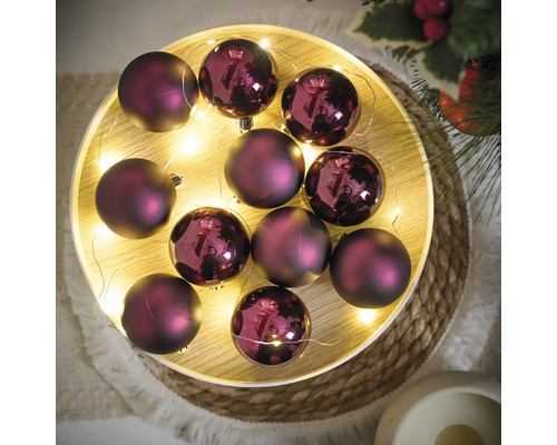 Dekorativní fialové vánoční koule se světelným řetězem na podnosu