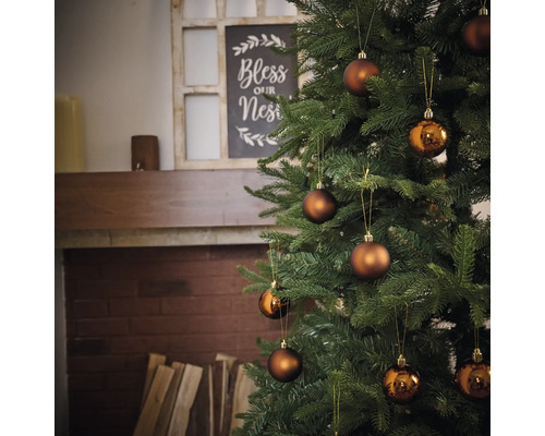 Zdobený vánoční strom s koulemi před krbem