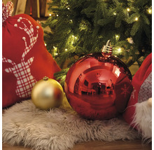 Vánoční dekorace s vánočními koulemi, dárková taška s motivem jelena a koberec z umělé kožešiny pod vánočním stromkem se světly.