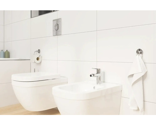 Světlá koupelna s toaletou, bidetem, ručníkem a držákem toaletního papíru