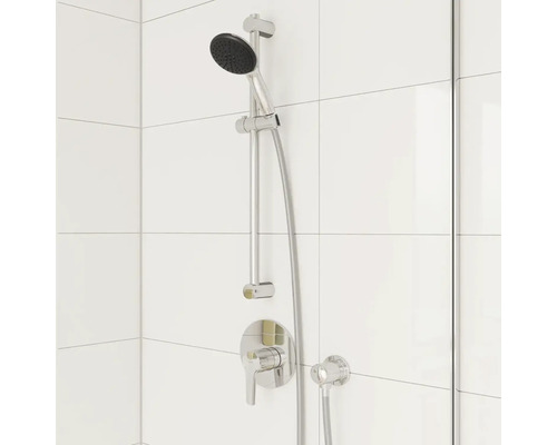 Sprchová souprava s ruční sprchou a sprchovou hadicí na bílé stěně