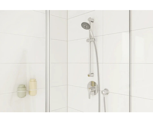 Detailní pohled na sprchu se sprchovou soupravou a dávkovačem mýdla na obložené stěně