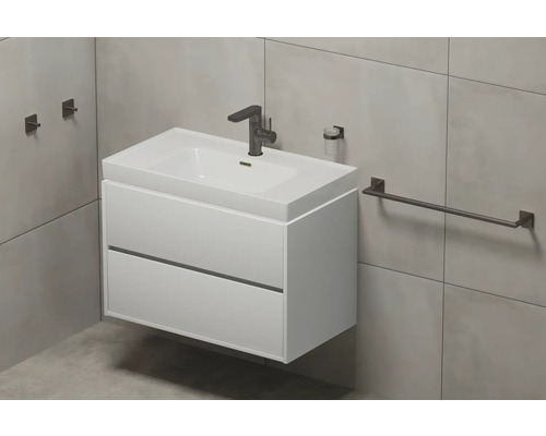 Bílé umyvadlo se dvěma zásuvkami, baterií, dávkovačem mýdla a držákem na ručníky v koupelně