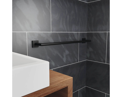 Černý držák na ručníky v koupelně s umyvadlem a šedými dlaždicemi