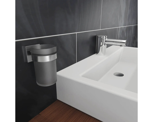 Detailní záběr umyvadla s kohoutkem a držákem na kelímek na zubní kartáčky v koupelně