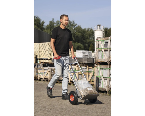 Muž přepravuje pytlované zboží s rudlem venku