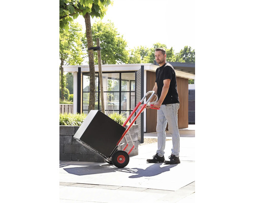 Muž přepravuje černý balík na rudlu venku.