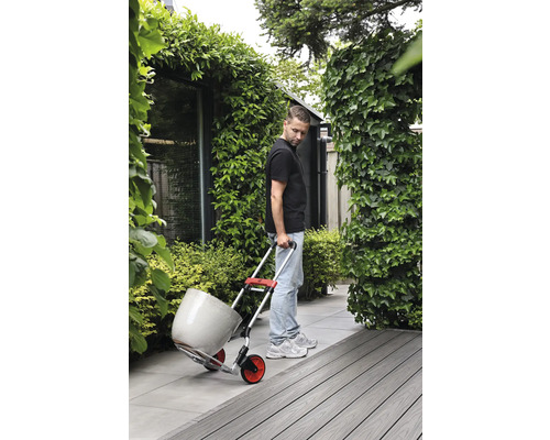 Muž přepravuje květináč s rudlem na zahradě.