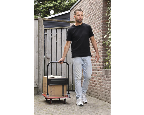 Muž táhne rudl s krabicemi na dlážděné cestě