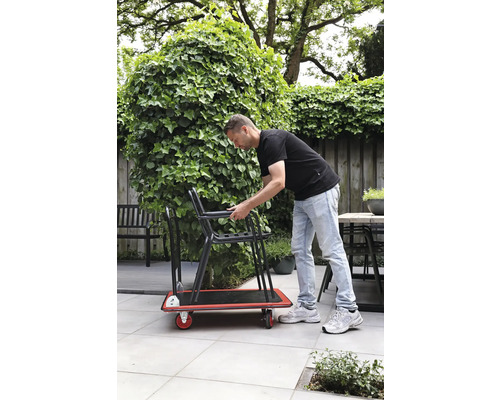 Muž přepravuje židle na rudlu na zahradě