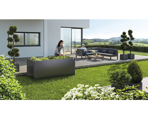 Zahradní scéna s květináčem, osázeným rostlinami, a sedící osobou na lavičce