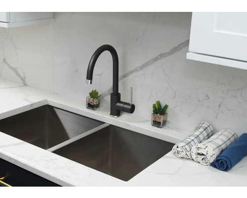 Kuchyňský dřez s černou vodovodní baterií, pracovní deskou a dvěma malými dekoracemi