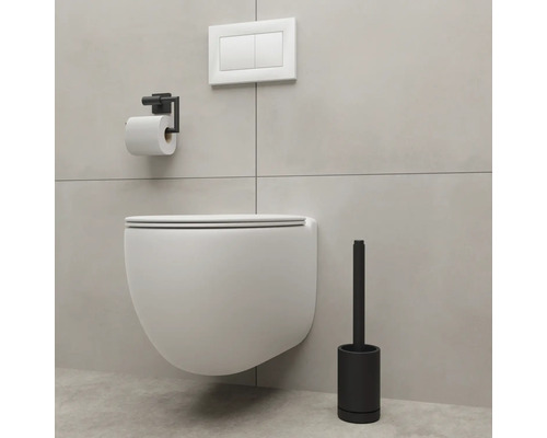 Závěsná toaleta s držákem na toaletní papír a toaletní kartáč v koupelně.