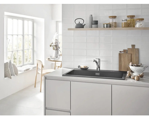 Světlá kuchyně s umyvadlem, baterií, dřevěnou policí s kuchyňským náčiním a nádobím