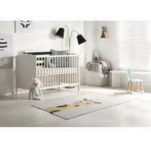 Světlý dětský pokoj s postýlkou, stojací lampou, dětskou židlí a kobercem se zvířecím motivem