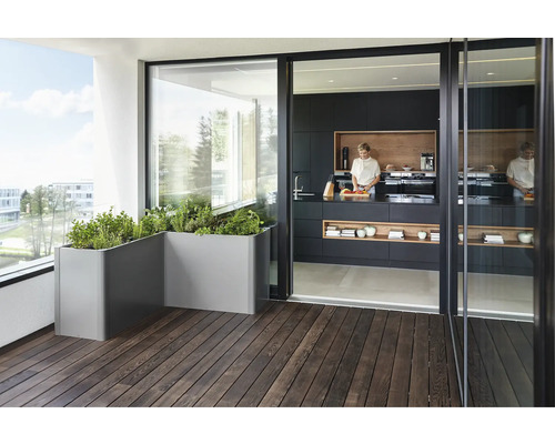 Balkon s truhlíky a kuchyně s vařící osobou