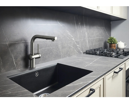 Kuchyňská scéna s dřezem, baterií a varnou deskou na pracovní desce s mramorovým vzhledem.
