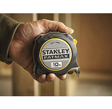 Svinovací metr Stanley Fatmax o délce 10 metrů držený v ruce.