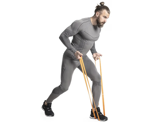 Muž cvičí s odporovou gumou a má na sobě sportovní oblečení