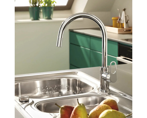 Kuchyňská scéna s kovovou dřezovou baterií, dřezem a ovocem