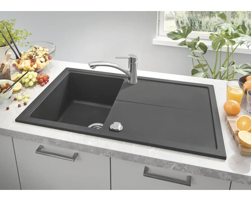 Tmavě šedý kuchyňský dřez s odkapávací plochou a vodovodní baterií na kuchyňské lince