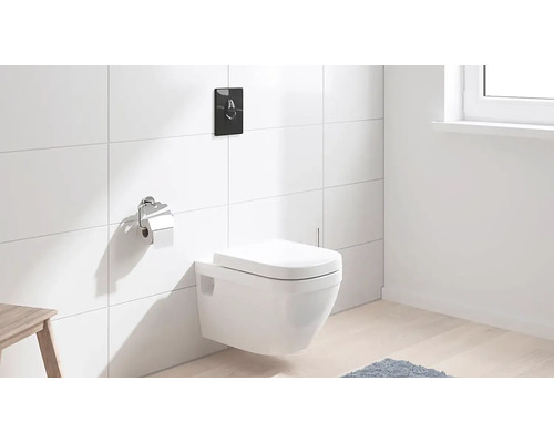 Závěsné WC s ovládací deskou a držákem toaletního papíru v koupelně s bílými obklady.