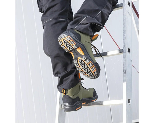 Osoba stoupá po žebříku v zelených bezpečnostních botách.