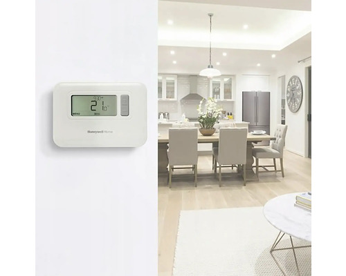 Pokoj s elektronickým termostatem pro regulaci teploty a logem Honeywell Home.