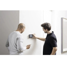 Dva muži instalují digitální termostat na zeď